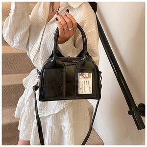 Détail du sac Boston en cuir verni noir avec doubles poignées et fente pour carte décorative