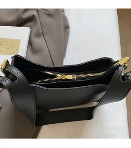 Detailed close-up of smooth gold metal zipper and hardware on a black leather bucket bag