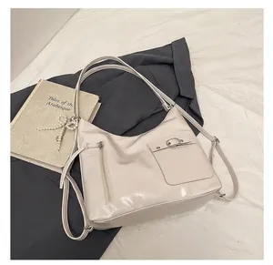 Detail view of cream hobo shoulder bag with metal buckles and pearl bow charm