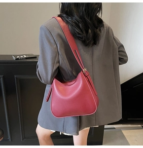 Detail of burgundy leather hobo bag with adjustable strap and side tassels on model
