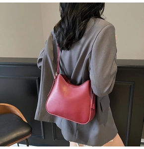 Detail shot of a dark red leather hobo tote bag with adjustable shoulder strap and tie accents