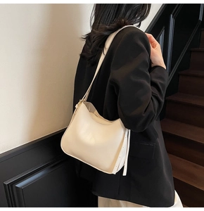 Side view of woman wearing a minimalist off-white crescent tote bag on stairs