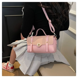Detail van roze lederen crossbodytas met geweven riet en gouden draaisluiting