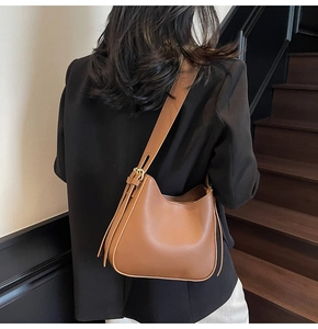 Close-up of caramel brown leather tote bag with adjustable strap and gold metal buckle
