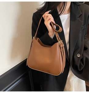 Detailed view of adjustable leather strap and metal buckle on brown saddle tote bag