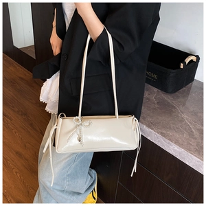 Detail of cream faux leather baguette shoulder bag with pearl bow and side ties