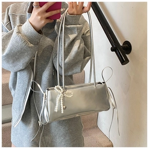 Detail van zilveren metallic handtas met parelstrik en trekkoord versieringen