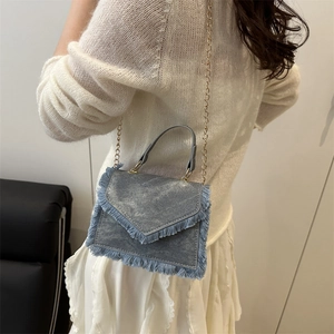 Petit sac bandoulière en denim bleu avec franges et chaîne dorée sur mannequin