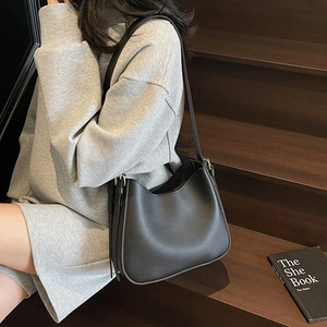 Minimalist black leather tote bag with side tassels and adjustable metal buckle