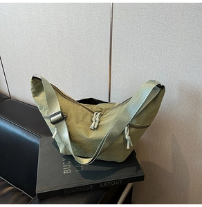 Detailed close-up of green nylon crescent bag with woven strap and knot zipper puller