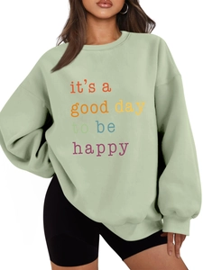 Detail of light green oversized sweatshirt with it's a good day to be happy text print