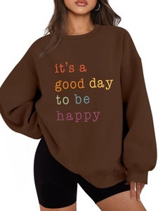 Detail of loose-fit brown sweatshirt featuring colorful 'it's a good day' print text