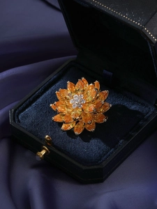 Gros plan d'une broche lotus à trois couches avec pierres jaunes en boîte à bijoux