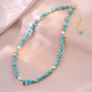 Detail of bohemian turquoise stone shards and white pearls on a silk background