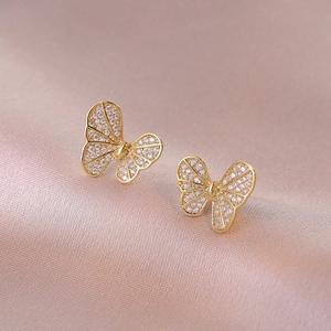 Sparkling butterfly stud earrings with rhinestones on a soft pink silk background
