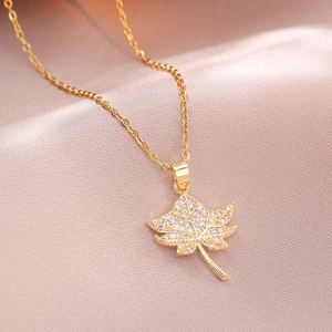 Elegant maple leaf pendant necklace with white zircons on soft champagne satin background