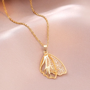 Golden double-layer wing pendant necklace with pavé zircons on elegant pink silk fabric