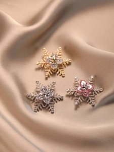 Detailed view of three spinning snowflake brooches with heart-shaped cubic zirconia on silk