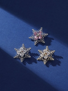 Detailed view of elegant snowflake brooches with rotating zircons in three color variants