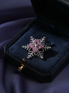 Detailed view of a silver snowflake brooch with pink heart zircon stones in a velvet box