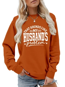 Close-up of orange crewneck sweatshirt featuring white printed slogan and star graphics