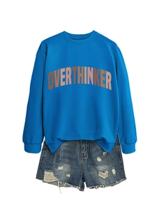 Detail of royal blue crewneck sweatshirt with OVERTHINKER print and distressed denim shorts