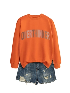 Detail of orange crewneck sweatshirt with OVERTHINKER print and ripped denim shorts