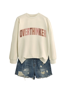 Detail of OVERTHINKER print on beige crewneck sweatshirt and ripped denim shorts texture