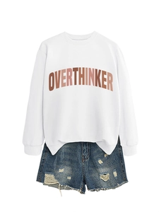 Detailed view of white sweatshirt with OVERTHINKER gradient print and distressed denim shorts