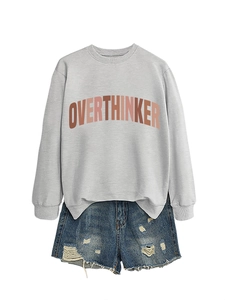 Detail of grey crewneck sweatshirt with OVERTHINKER print and distressed denim shorts