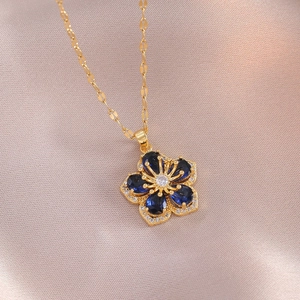 Collier fleur dorée élégant avec pétales bleus et cristaux de zircon sur tissu en soie