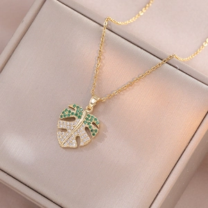 Golden monstera leaf pendant necklace with green and white cubic zirconia crystals