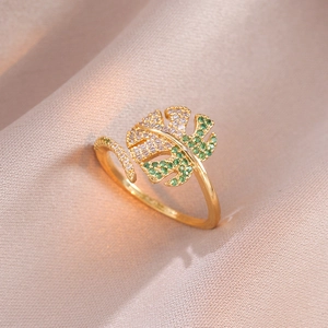 Macro detail of golden monstera leaf ring with pavé green and white zircon crystals