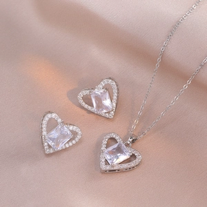 Elegant zircon heart necklace and earrings set on purple silk background