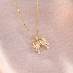 Elegant gold titanium necklace with a bow pendant paved in zircons and rectangle gemstone