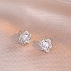 Sparkling silver star stud earrings with round cut zircon stones on champagne silk