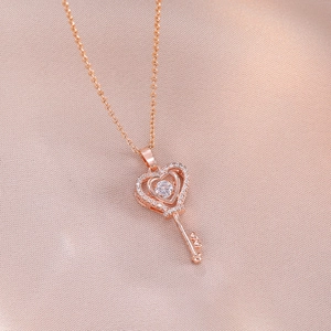 Rose gold heart key pendant necklace with sparkling diamonds on pink silk fabric background