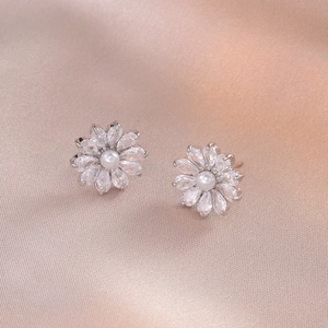 Elegant flower stud earrings with zircon petals and pearls on champagne silk background