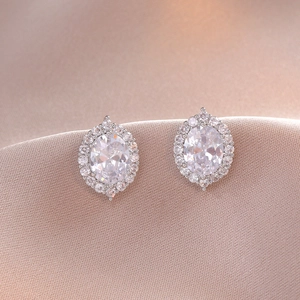 Elegant silver halo stud earrings with oval-cut cubic zirconia on pink silk fabric