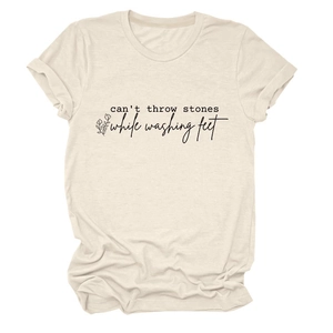 Détail des manches retroussées et texte imprimé sur un t-shirt beige à col rond