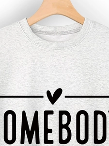 Detail of grey crewneck sweatshirt with black HOMEBODY slogan and heart on a wooden hanger