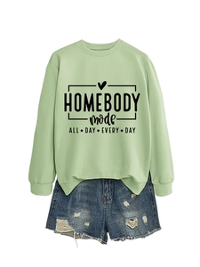 Detail of sage green sweatshirt with Homebody Mode print and distressed denim shorts