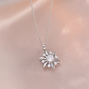 Elegant silver snowflake necklace with sparkling marquise zircon on pink silk fabric background