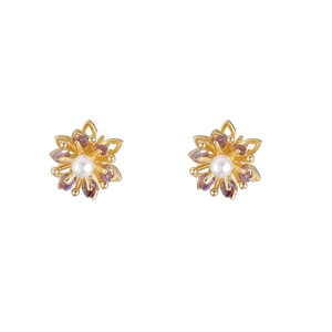 Détail de boucles d'oreilles fleur dorées avec gemmes violettes et perle blanche centrale