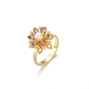 Détail d'une bague fleur avec perle centrale et pétales de pierres violettes dorées