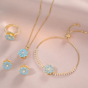 Golden daisy jewelry set with light blue enamel petals and sparkling crystal accents