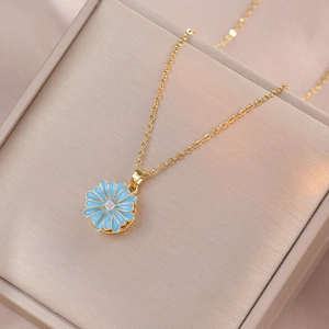 Detail of a light blue enamel daisy pendant with a gold chain on champagne velvet