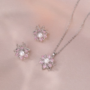 Détail du collier et boucles d'oreilles fleur avec zircons roses et perles blanches