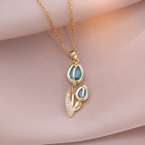 Close-up of golden tulip pendant with blue buds and sparkling zircon leaves on silk