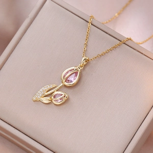 Elegant gold tulip pendant necklace with pink zircon gemstones on jewelry box background